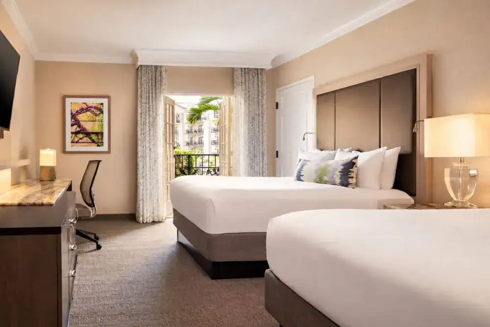 Guest room with two beds and a balcony overlooking the indoor atrium.