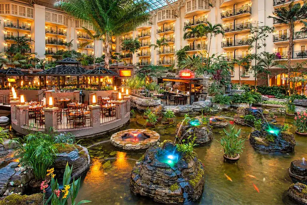 Dining area at Gaylord Opryland Resort in Nashville, surrounded by indoor gardens, fountains, and guest room balconies.